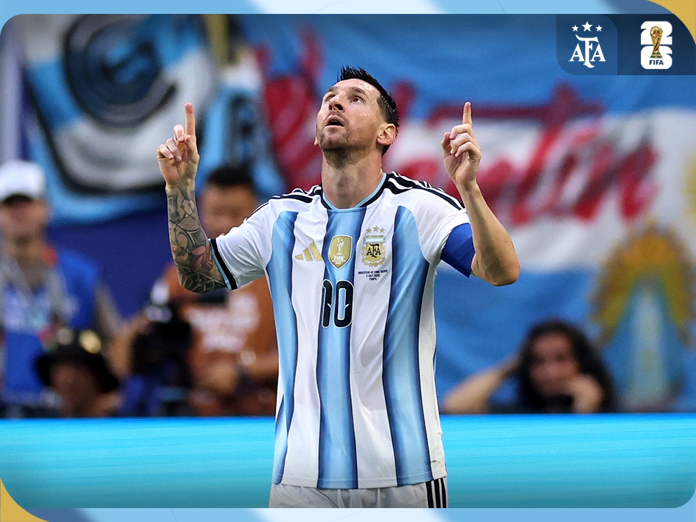 Lionel Messi in Argentina's number 10 shirt, pointing both hands toward the sky on the pitch